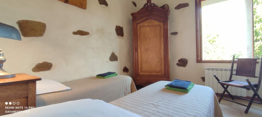 Chambre parentale du gîte L'Orangeraie avec deux lits simples (70x190), mobilier ancien, vue sur le jardin.