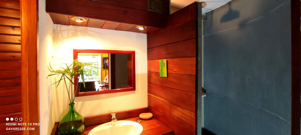 Salle de bain du gîte Le Pénéquet : douche à l'italienne parois zinc, pommeau arrosoir provençal, sol galets, Le Pradet.