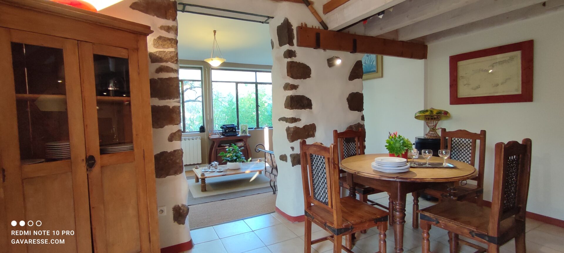 Grand séjour salon du gîte L'Orangeraie avec murs en pierres, coin repas, et vue sur le salon lumineux, Le Pradet.