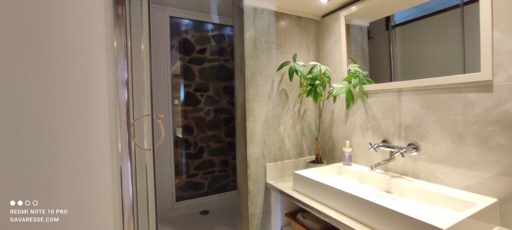 Salle de bain du gîte L'Orangeraie, vasque en béton ciré, douche à l'italienne avec murs en pierre apparents, Le Pradet.