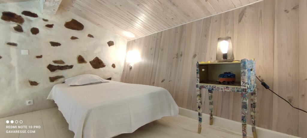 Lit simple sur la mezzanine de la chambre parentale de La Fenière, avec vue sur les poutres, Le Pradet.