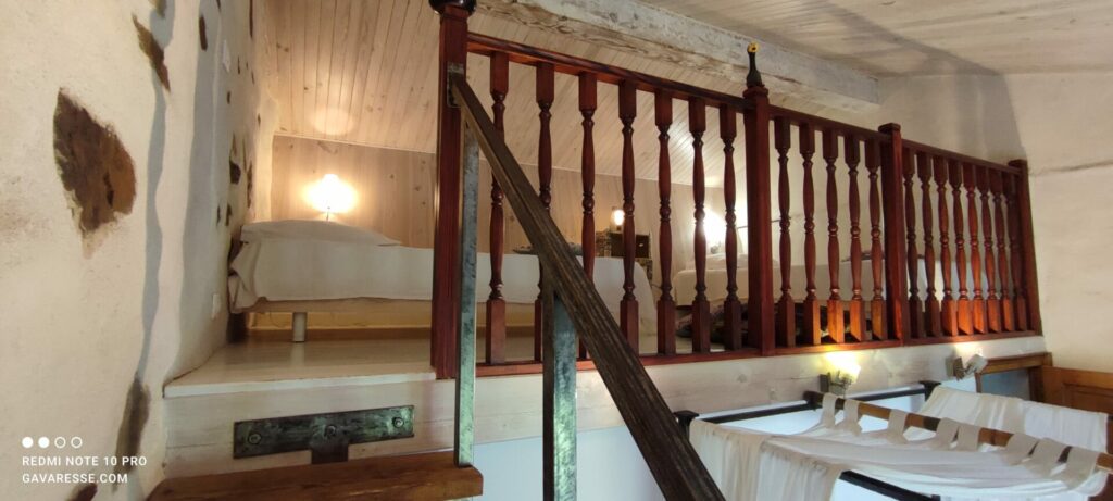 Vue d'ensemble de la mezzanine de la chambre parentale de La Fenière, avec literie et rambardes anciennes, Le Pradet.