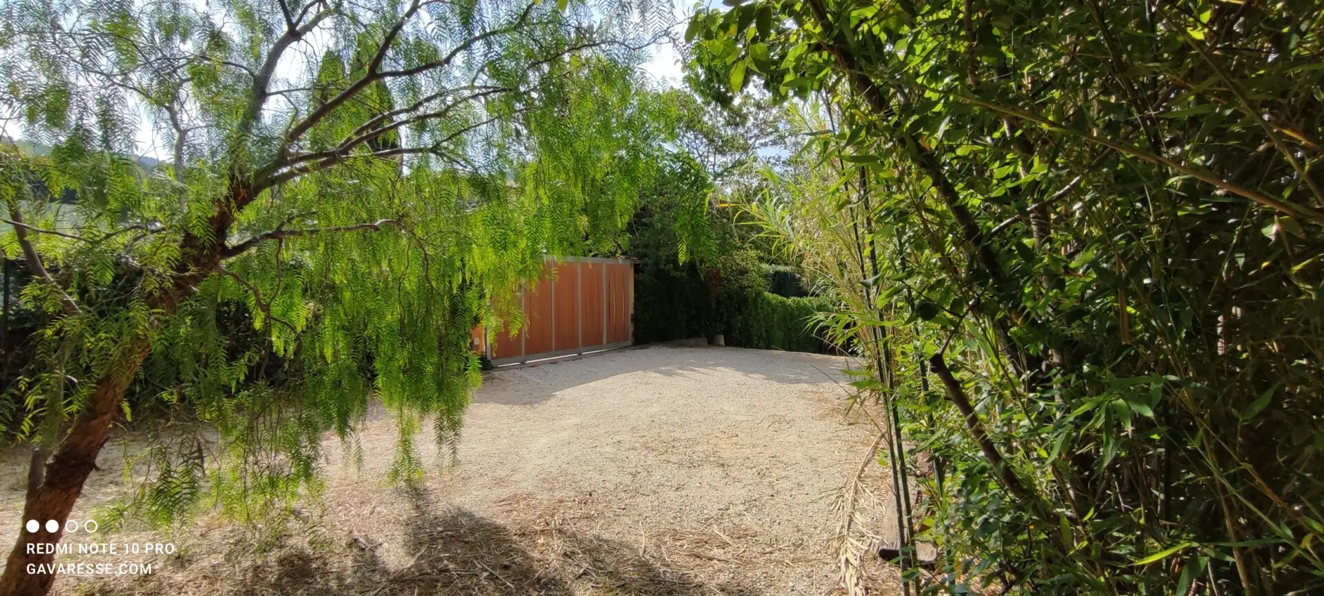Autre perspective du parking clos du Mas de la Gavaresse, montrant son intégration dans le jardin et sa capacité d'accueil pour plusieurs voitures.